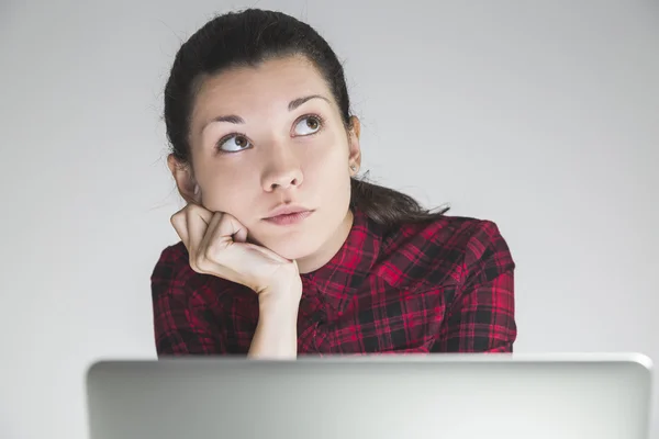 Young woman in red dress dreaming in front of her laptop — Stockfoto