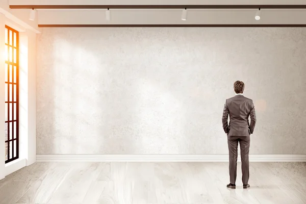 Vista trasera del hombre de negocios mirando a la pared en blanco de su oficina — Foto de Stock