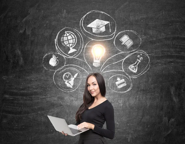 Meisje met computer en onderwijs schetsen op schoolbord — Stockfoto