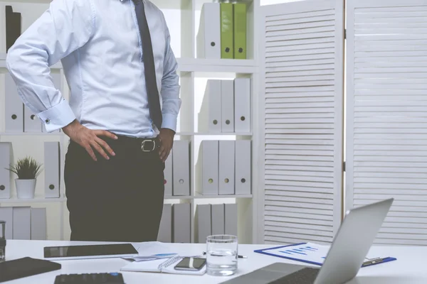 Podnikatel v modré košili stojí ve své kanceláři — Stock fotografie