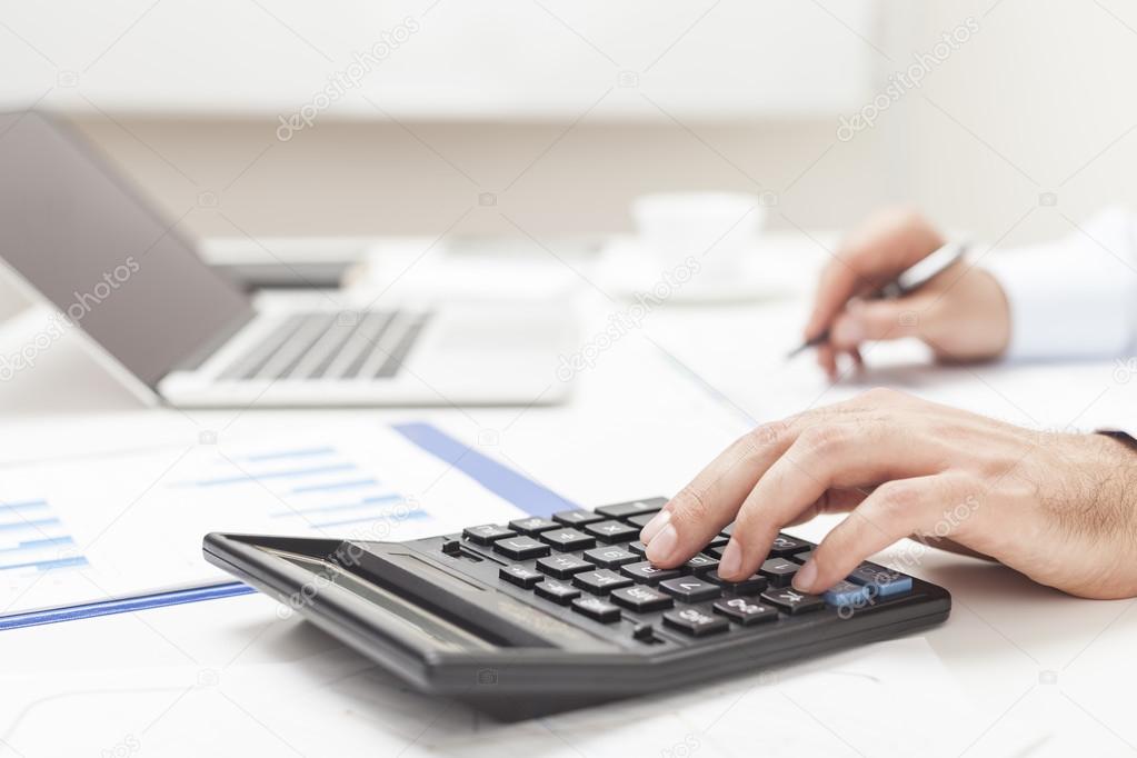 Side view of man's hands using calculator