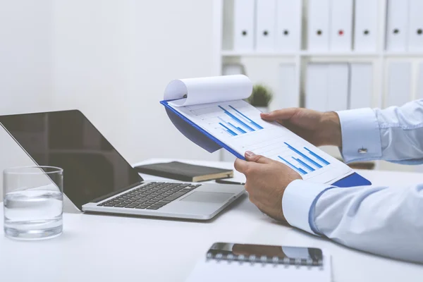 Man holding clipboard with two graphs — Stock Photo, Image