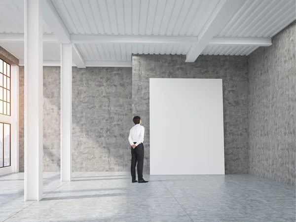 Hombre mirando afiche vertical en loft con pilares — Foto de Stock