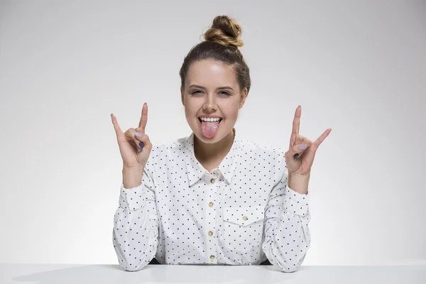 La chica con la lengua afuera está sentada a la mesa — Foto de Stock