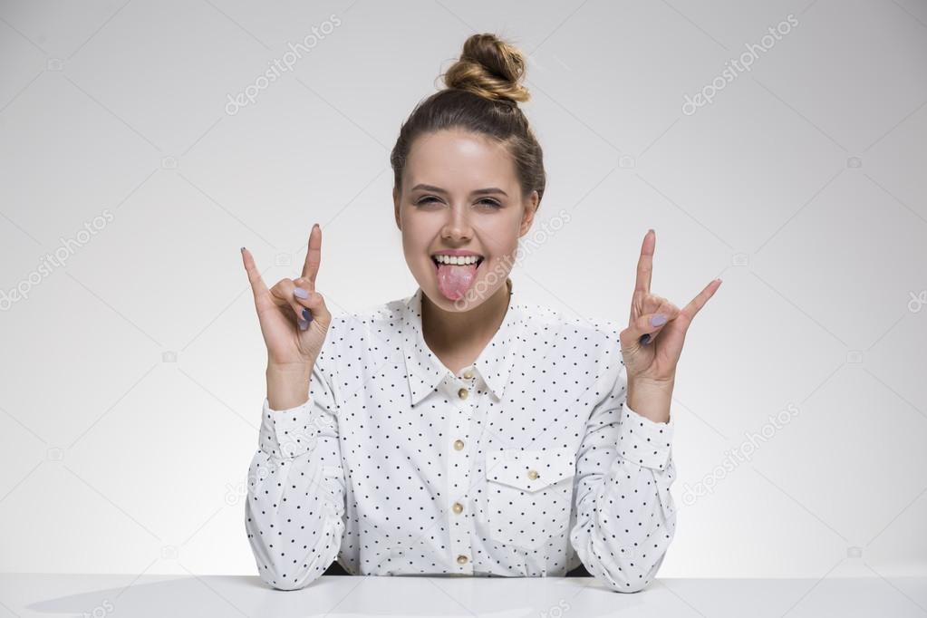 Girl with her tongue out is sitting at the table