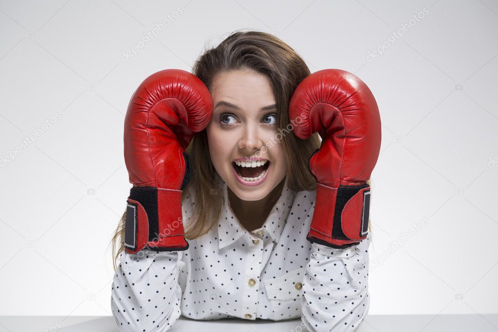 Scared girl in polka shirt wearing boxing gloves