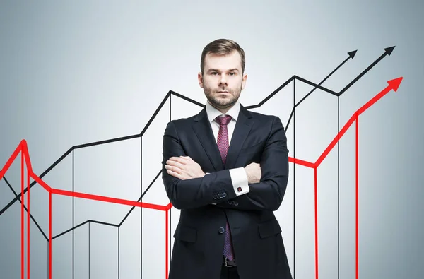 Hombre de negocios serio y tres gráficos en crecimiento en la pared gris — Foto de Stock