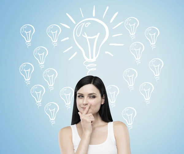 Woman with black hair against blue wall with light bulbs — Stock Photo, Image