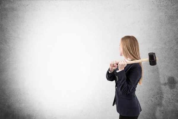 Woman is smashing concrete wall with sledgehammer — Stock Photo, Image