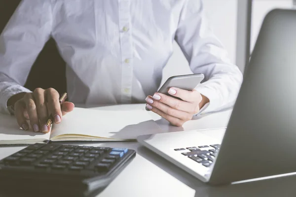 Primer plano de la mujer sosteniendo el teléfono celular y tomando notas —  Fotos de Stock