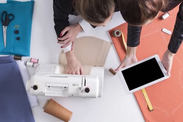 女性は、彼女の同僚と縫製にタブレットを見せています。 — ストック写真