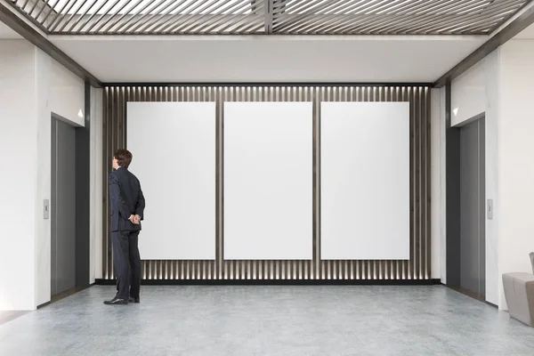 Mann wartet auf Aufzug in Lobby mit drei großen senkrechten Pfosten — Stockfoto