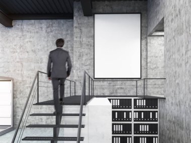 Man looking at wall in office with stairs and poster clipart