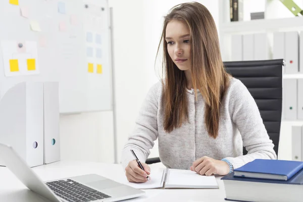 Zentrierte Sekretärin schreibt und schaut auf Laptop — Stockfoto