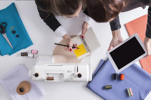 Women with tablet and notebook are about to start sewing — Stock Photo, Image