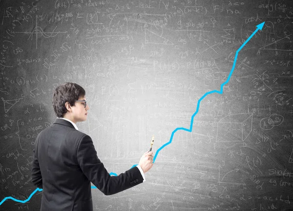 Businessman drawing a blue graph with a marker on blackboard — Stock Photo, Image