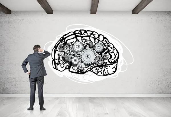 Businessman looking at brain with cogs — Stock Photo, Image