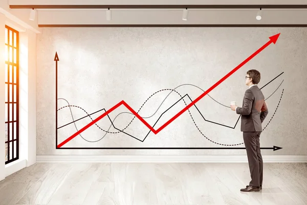 Man with coffee is looking at graphs in concrete room — Stock Photo, Image