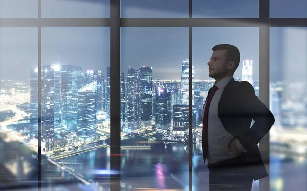 Чоловік дивиться на нічне місто через вікно — стокове фото