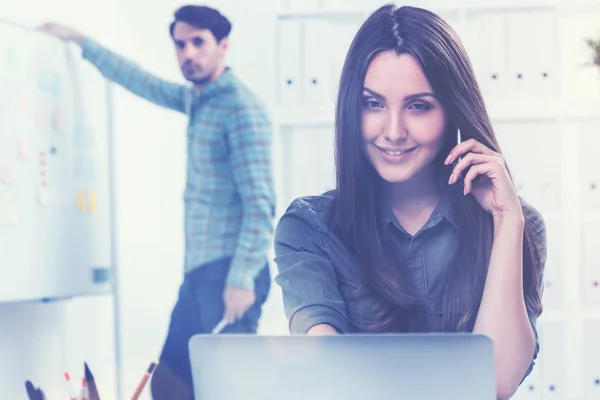 Mujer sonriente al teléfono y un hombre en la oficina —  Fotos de Stock