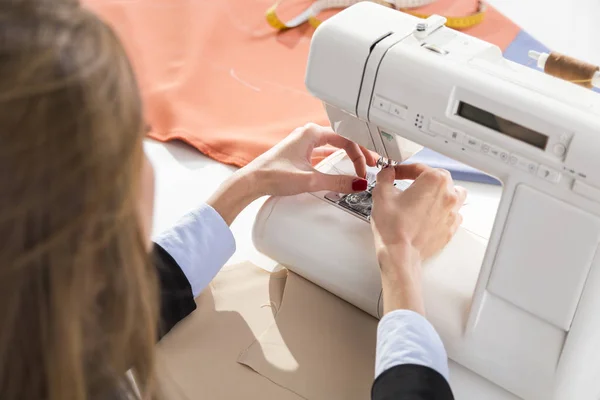 Frau legt einen Faden in eine Maschine — Stockfoto