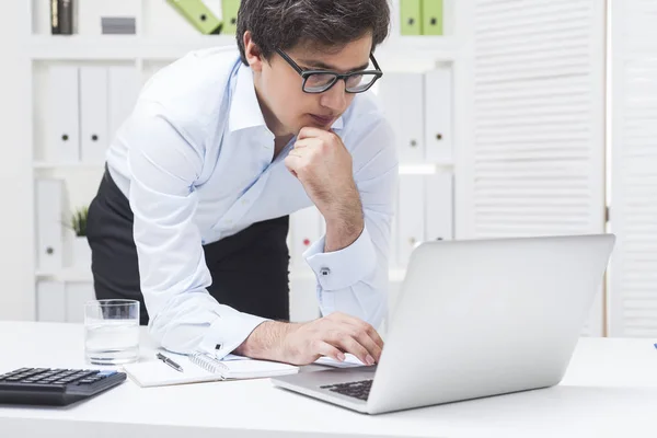 Man leaning at his desk, thinking and typing — Stock Photo, Image