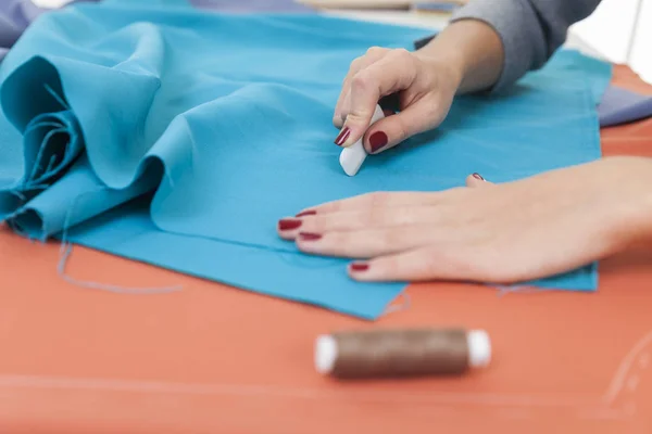 Kvinnans händer rita ett mönster på ljusa blå material — Stockfoto