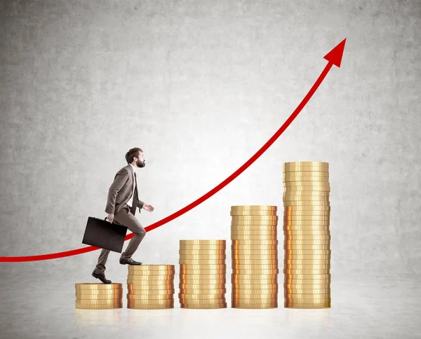 Businessman in suit with a case climbing stacks of coins — Stock Photo, Image