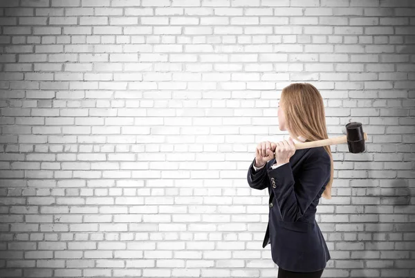 Mulher batendo parede de tijolo branco com marreta — Fotografia de Stock