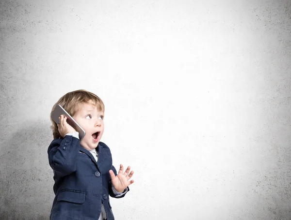 Söta lilla barn på telefonen nära en betongvägg — Stockfoto