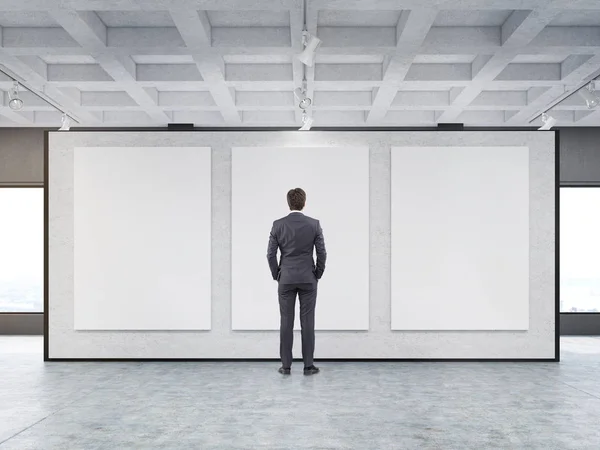 Man looking at three posters in a gallery — Stock Photo, Image