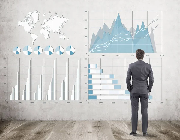 Empresario de traje está examinando tres gráficos en una pared de hormigón — Foto de Stock
