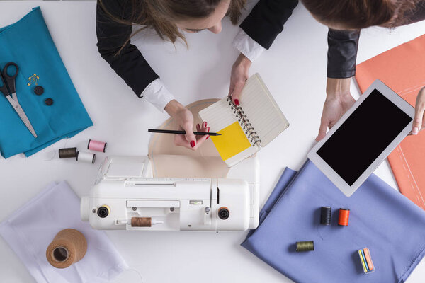 Businesswomen with tablet and notebook are about to start sewing