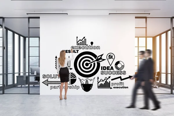 Woman drawing a business poster in a corridor with two meeting r
