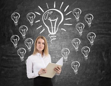 Ampul kaşar ile kara tahta yakınındaki bir dizüstü olan sarışın kadın