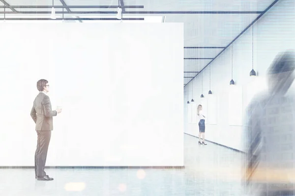 Men and a woman are looking at empty banners in an art gallery, — Stock Photo, Image