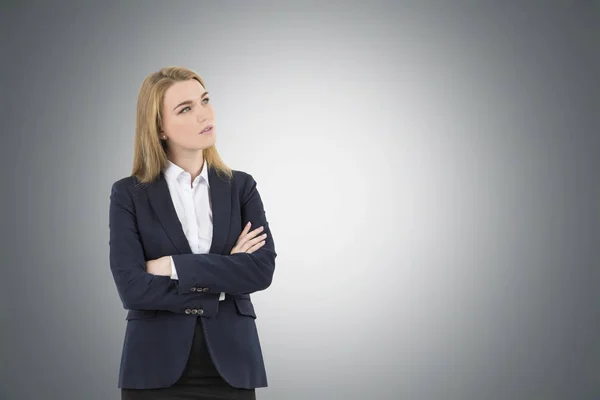 Mujer rubia con brazos cruzados cerca de una pared gris — Foto de Stock