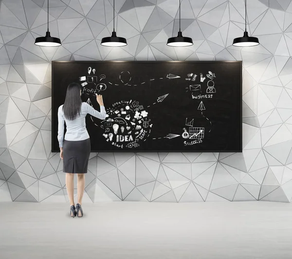 Woman with black hair is drawing sketch in dark concrete room wi — Stock Photo, Image