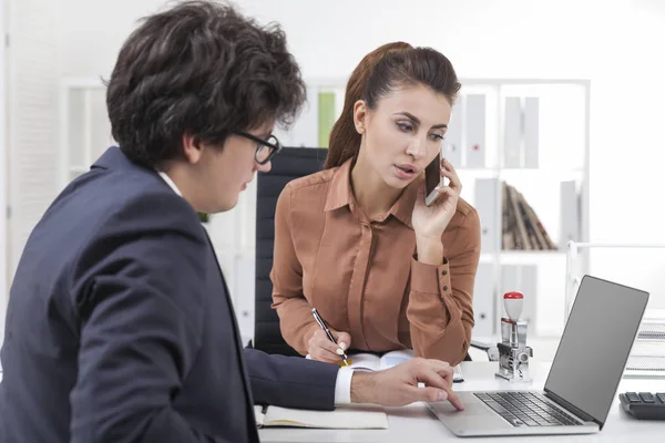 Uomo che lavora al computer portatile, donna al telefono — Foto Stock