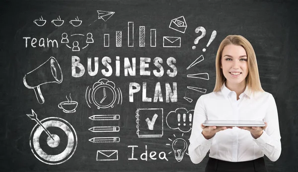 Geschäftsfrau mit Tablet in der Nähe von Businessplan-Symbolen auf Blackboa — Stockfoto