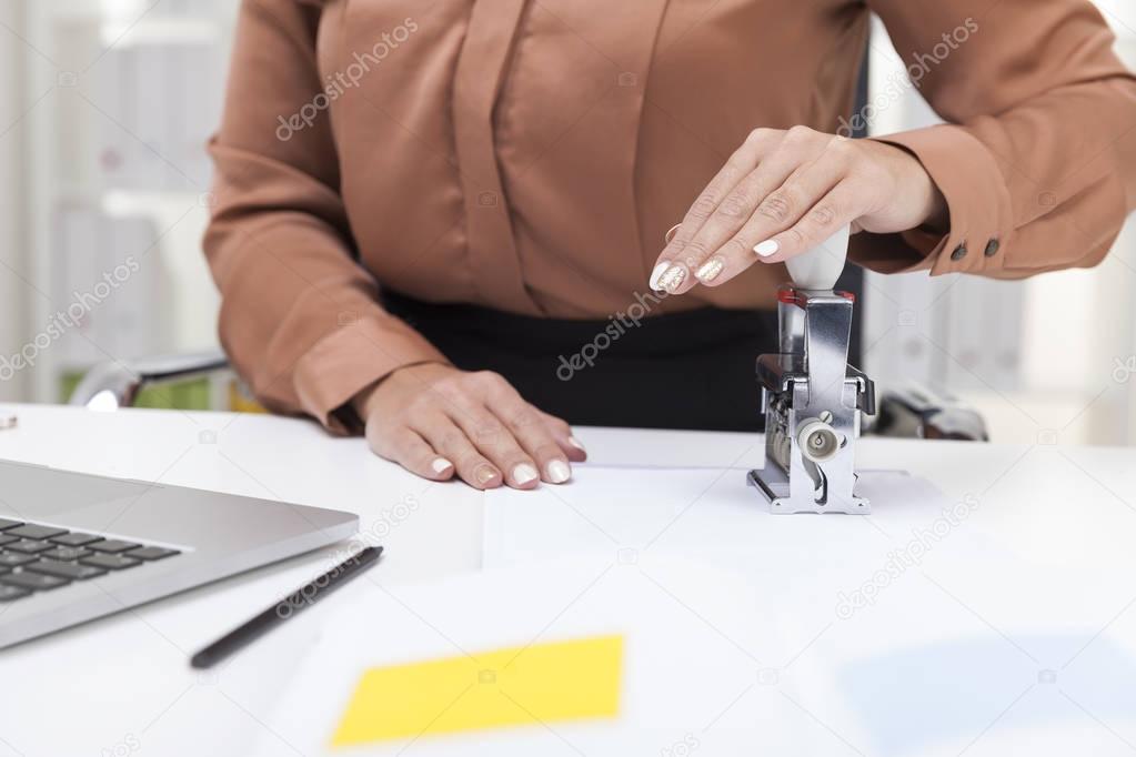 Woman in brown blouse is using a stamp