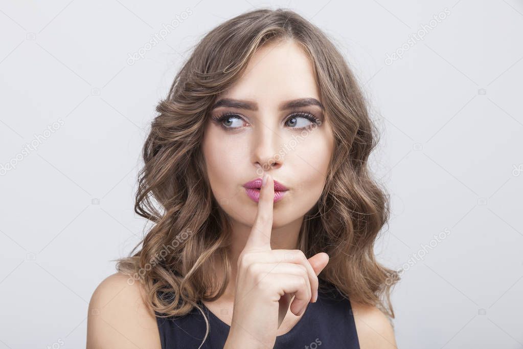 Woman with her finger near pink lips
