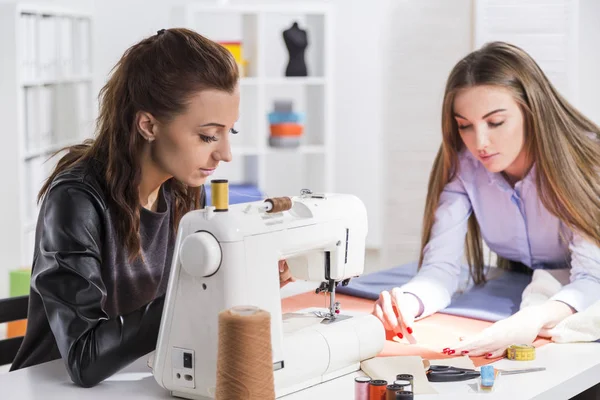 Mujer cosiendo, colega está haciendo un patrón — Foto de Stock