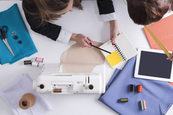 Woman is showing her notebook to her colleague with a measuring 