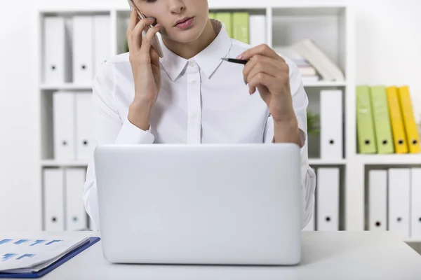 Närbild av en kvinna i en vit blus på hennes mobil på ett kontor — Stockfoto