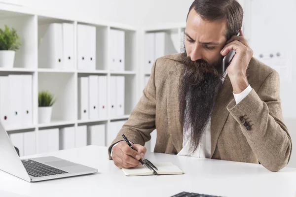 Un hombre de negocios con barba larga está en su teléfono — Foto de Stock