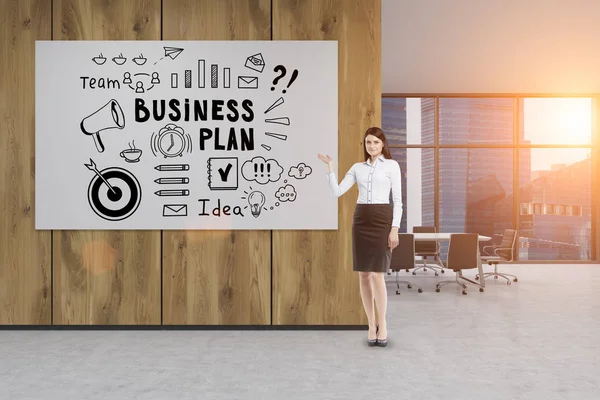 Businesswoman in an office with a business plan poster — Stock Photo, Image
