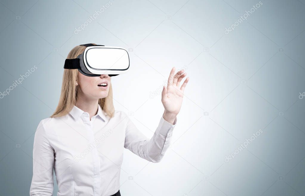 Blond woman in vr glasses near a gray wall