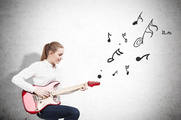 Woman with an electric guitar near a concrete wall with note ske — Stock Photo, Image