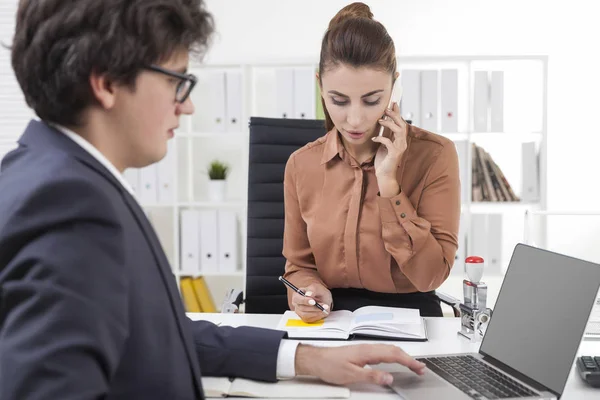 Kvinnan pratar på sin telefon och ta anteckningar. Man att skriva — Stockfoto